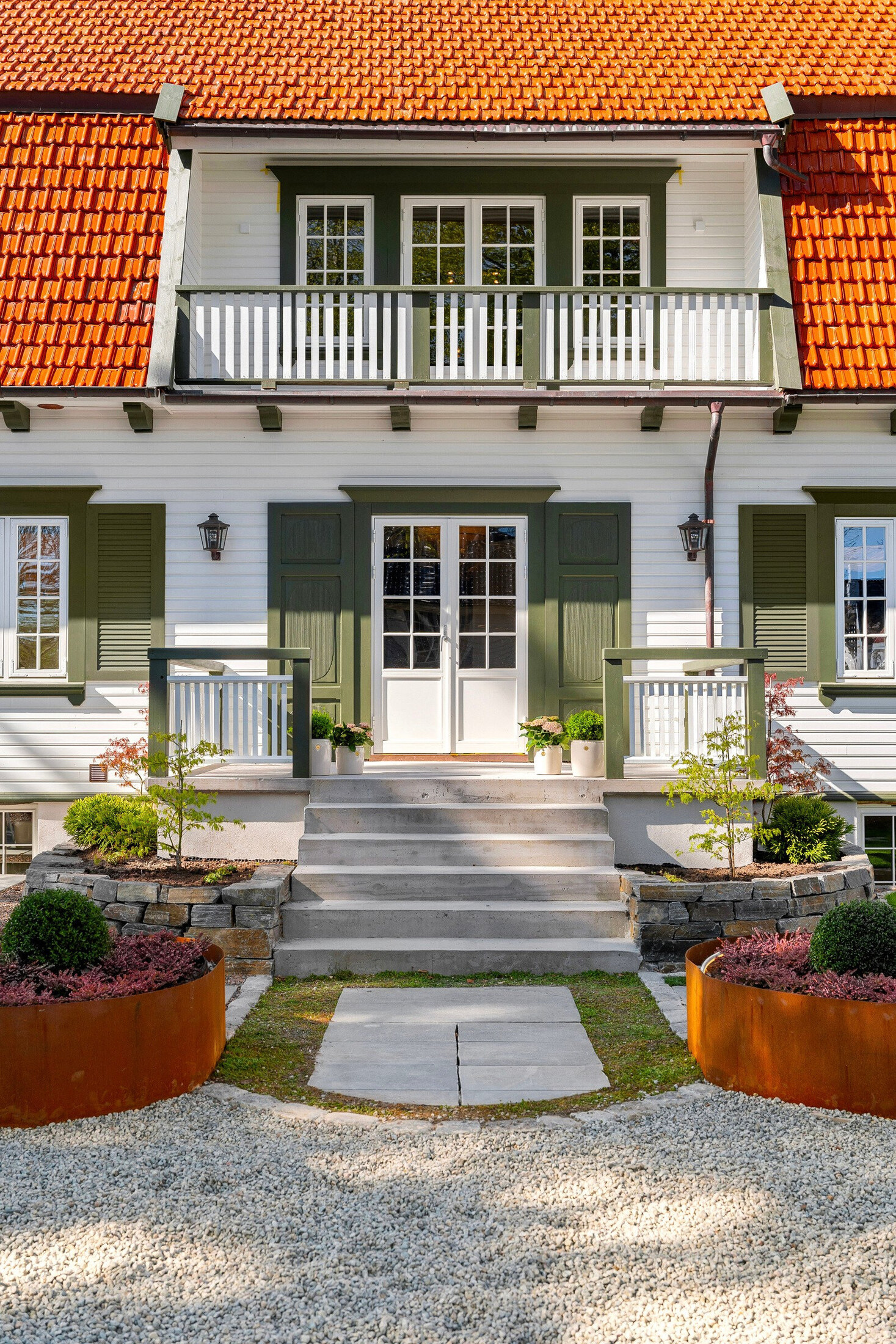Hovedinngangen med bred trapp i naturstein og cortenkantede plantebed