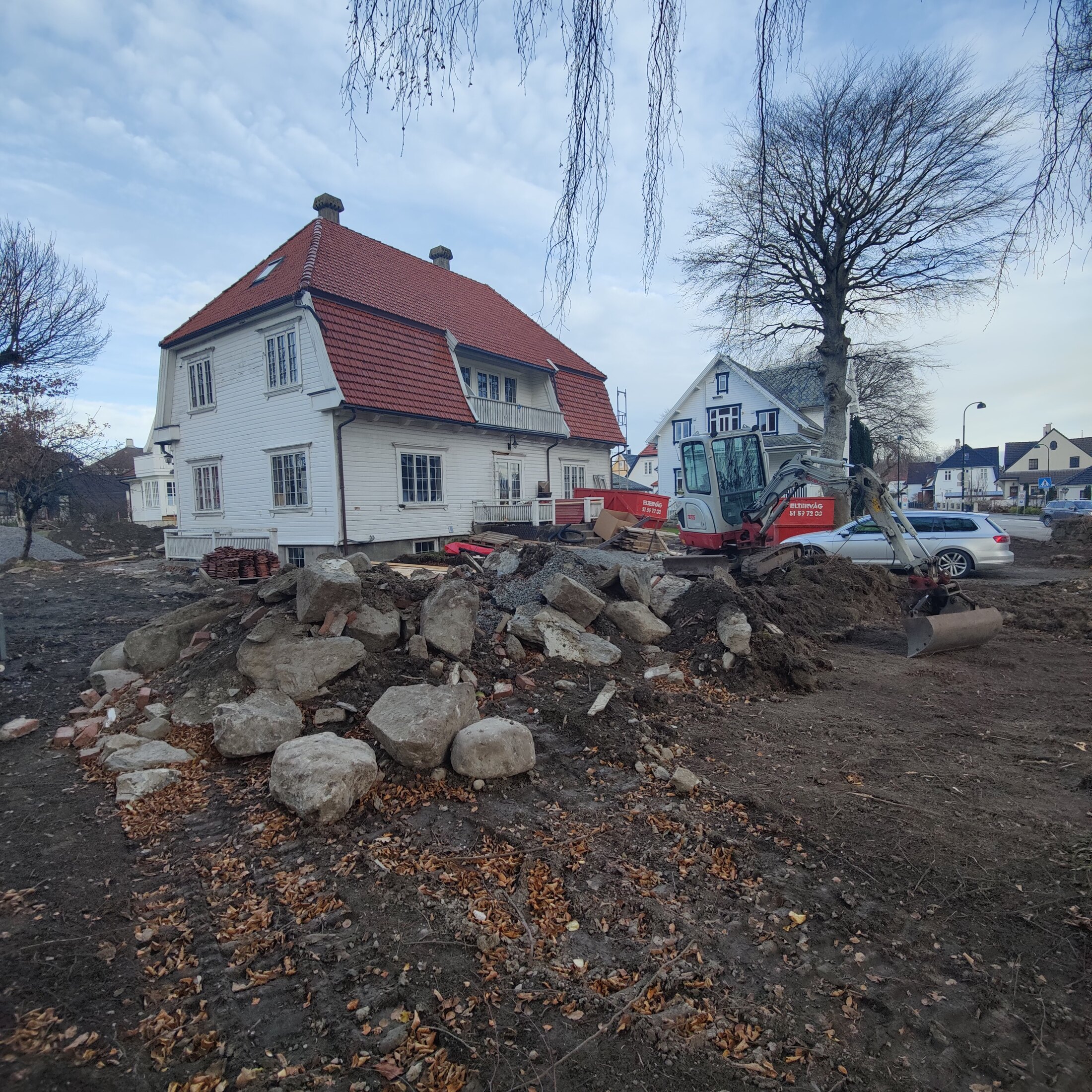 Steinmasser og gravemaskin foran huset under anleggsfasen
