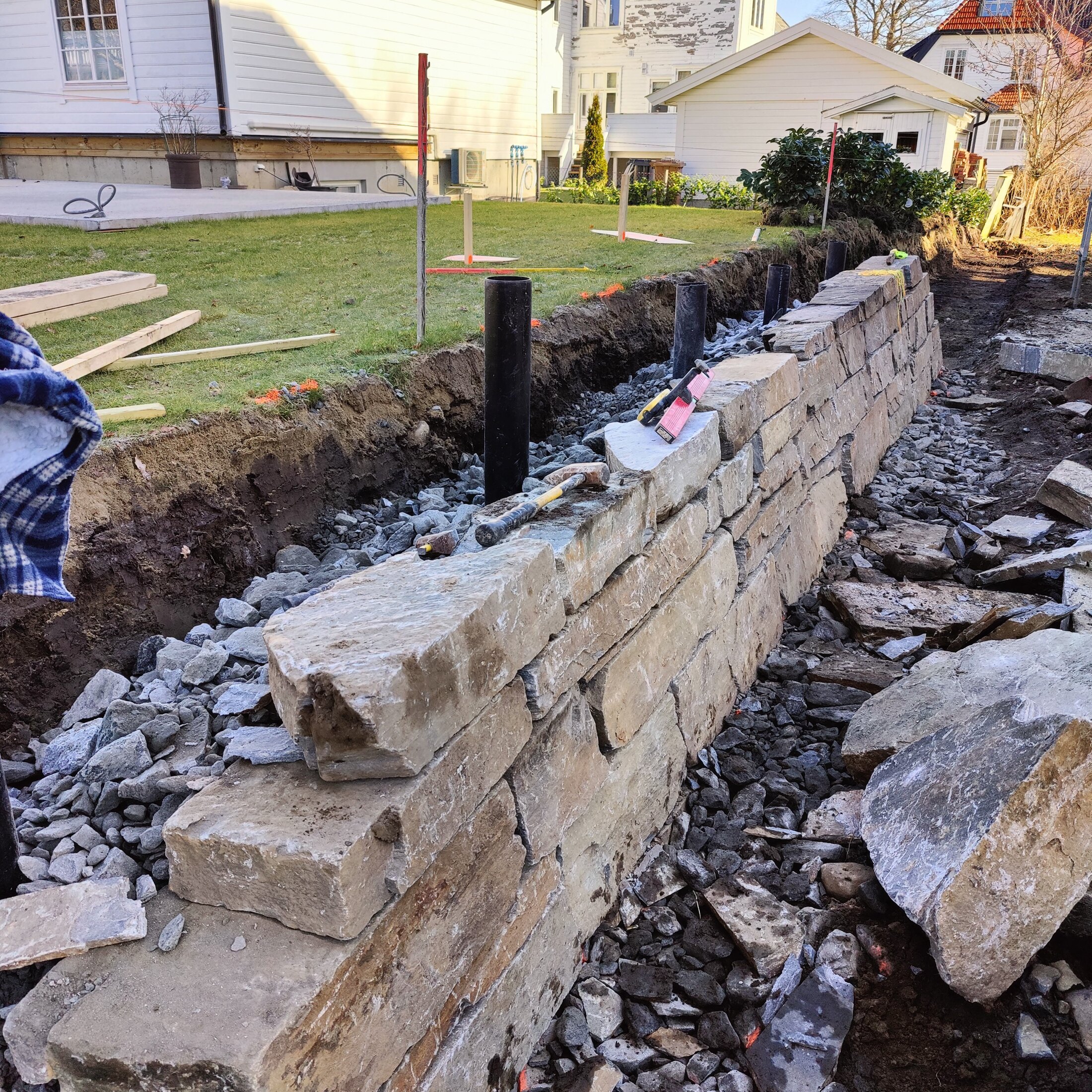 Natursteinsmuren under oppbygging med drenerende pukk bak muren