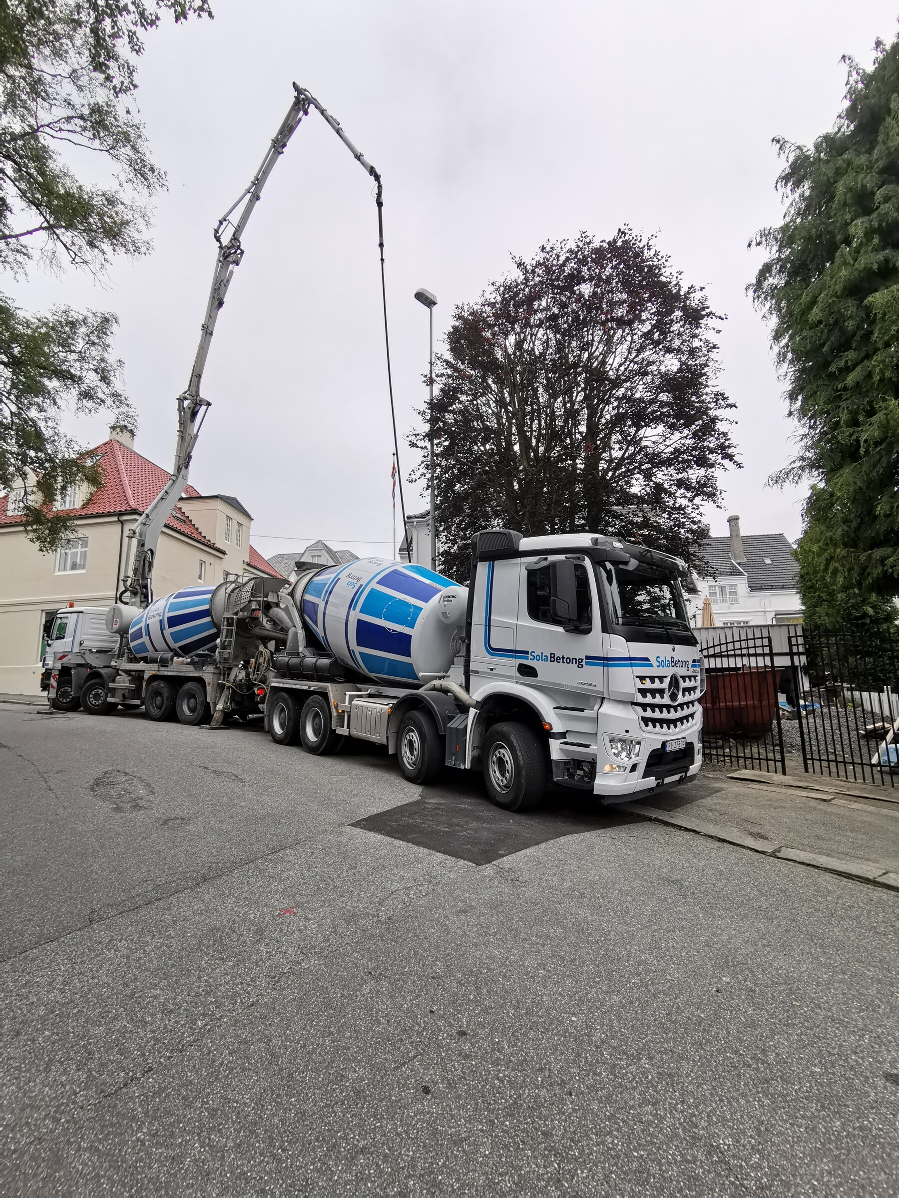 Betongbil og betongpumpe i arbeid utenfor bygget