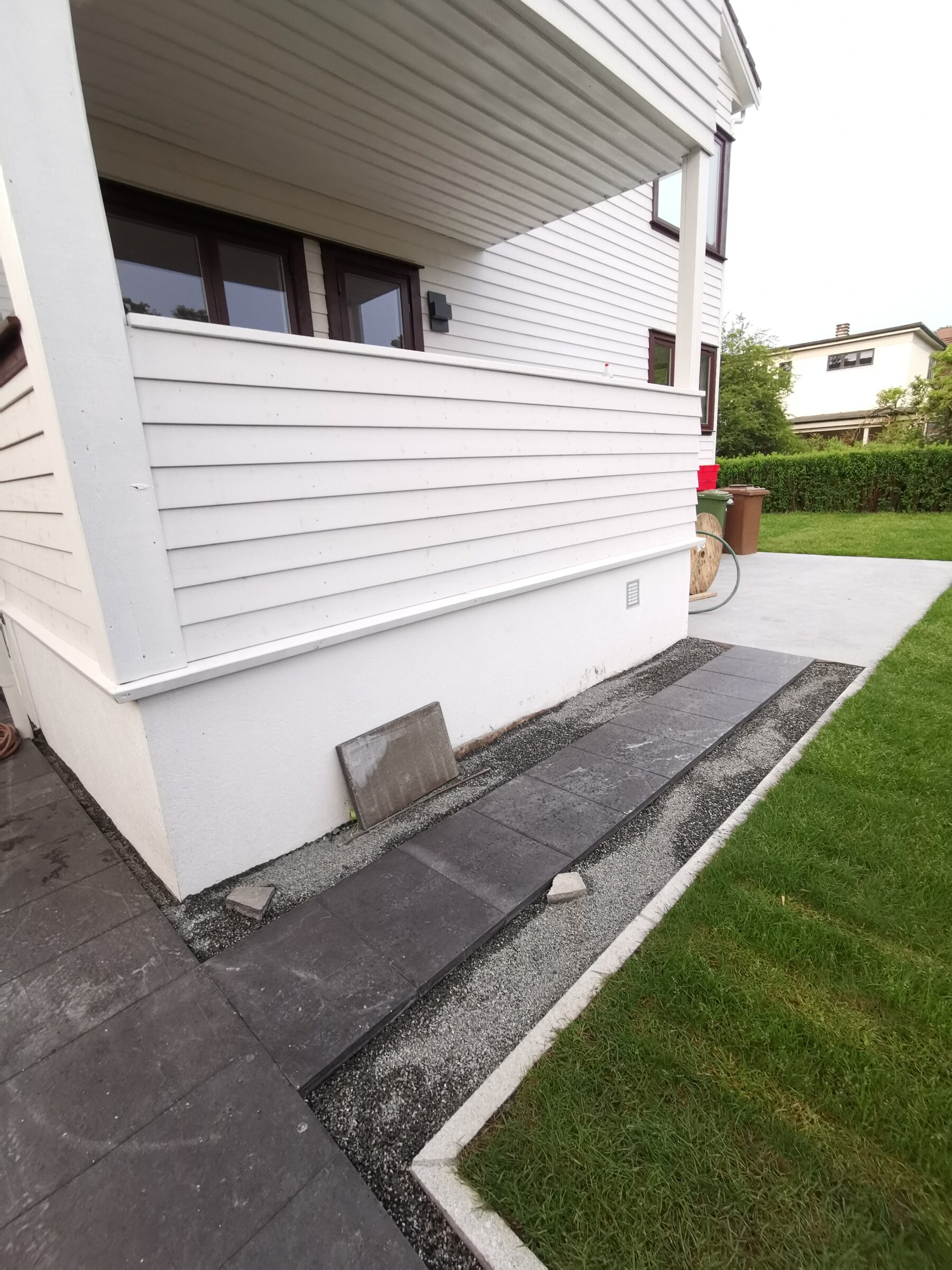 Maskinglattet betongflate langs huset med plen og granittkant