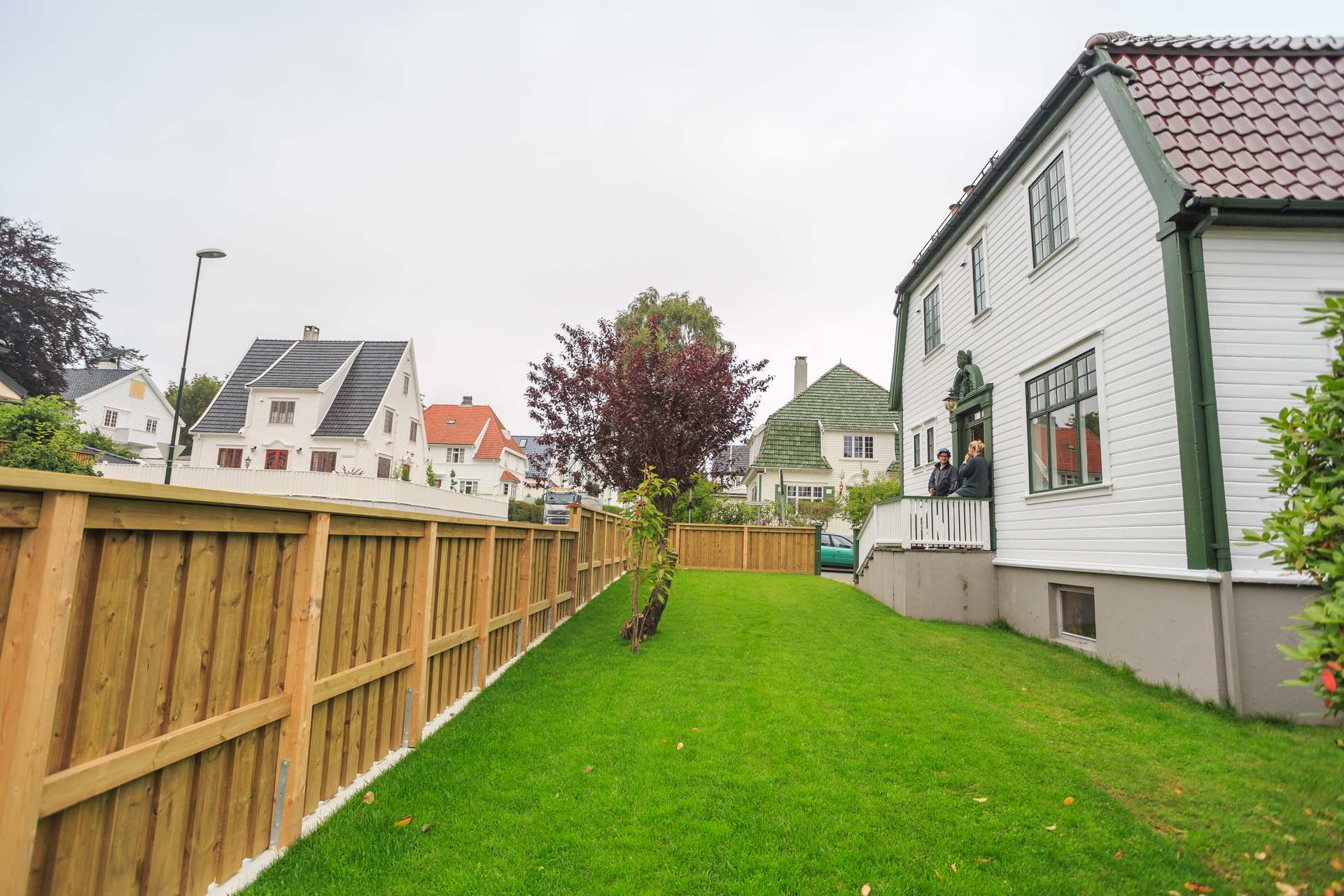 Støpt støttemur med tregjerde sett langs grensen