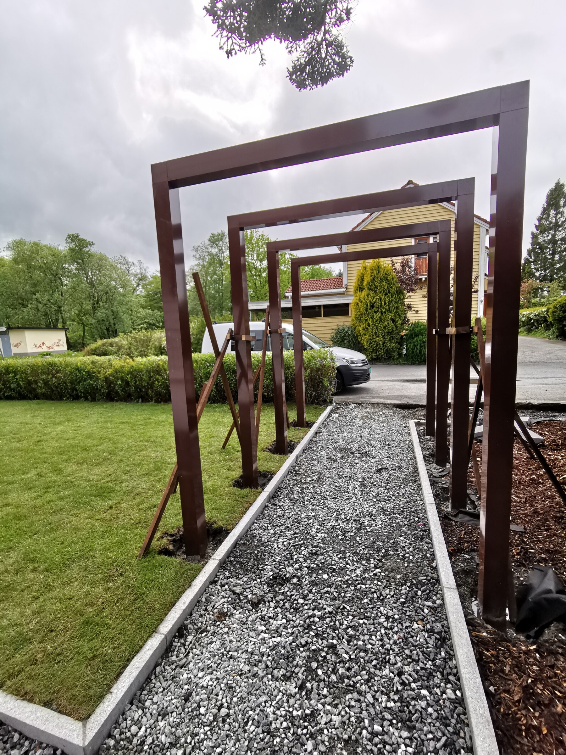 Portaler langs grusgangen med den ferdige plenen ved siden av
