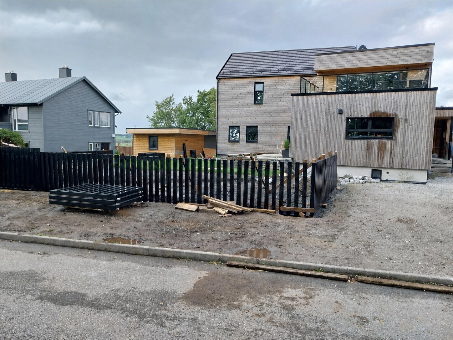 Tidlige hagearbeider med gjerdeseksjoner i aluminium og klargjort grunn