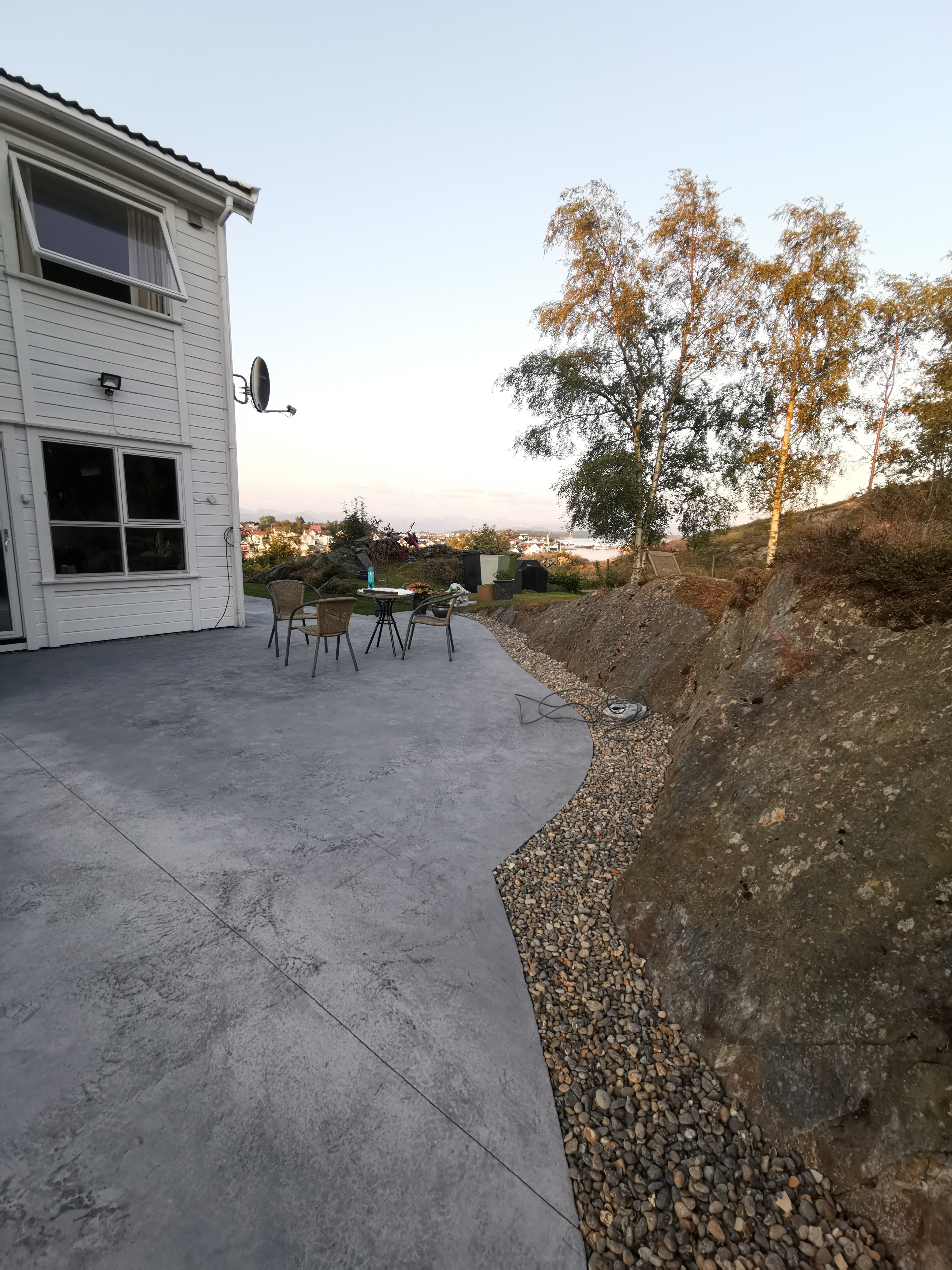 Ferdig betongdekke med hagemøbler og myk avslutning mot terrenget