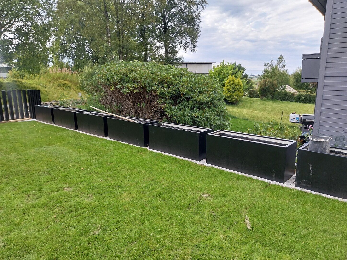 Ferdig plen ved siden av en rekke svarte, pulverlakkerte spesialbygde plantekasser
