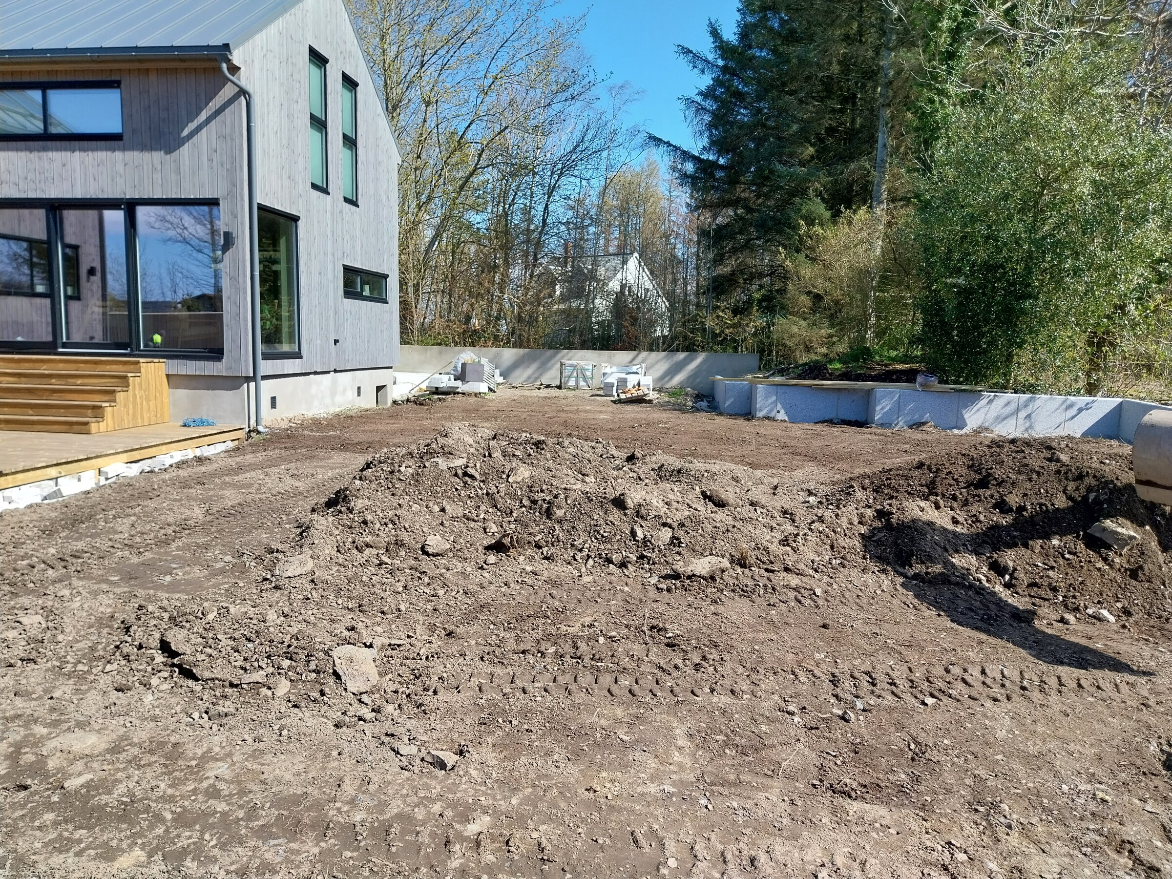 Nybygget terrasse i tre med ubearbeidet jord og masser rundt